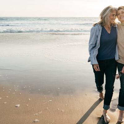 Zwei Seniorinnen gehen am Meer spazieren.