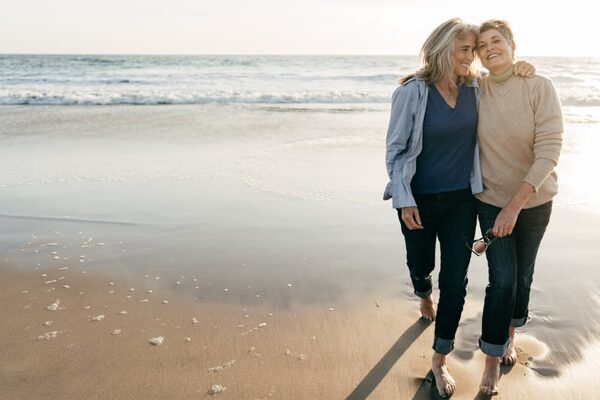 Zwei Seniorinnen gehen am Meer spazieren.