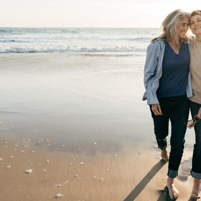 Zwei Seniorinnen gehen am Meer spazieren.