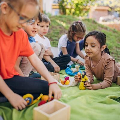 Gruppe spielender Grundschulkinder draußen, davon zwei mit Brille.