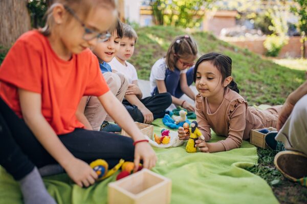 Gruppe spielender Grundschulkinder draußen, davon zwei mit Brille.