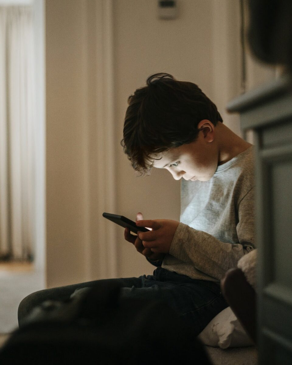 Junge sitzt zuhause und schaut auf sein Smartphone