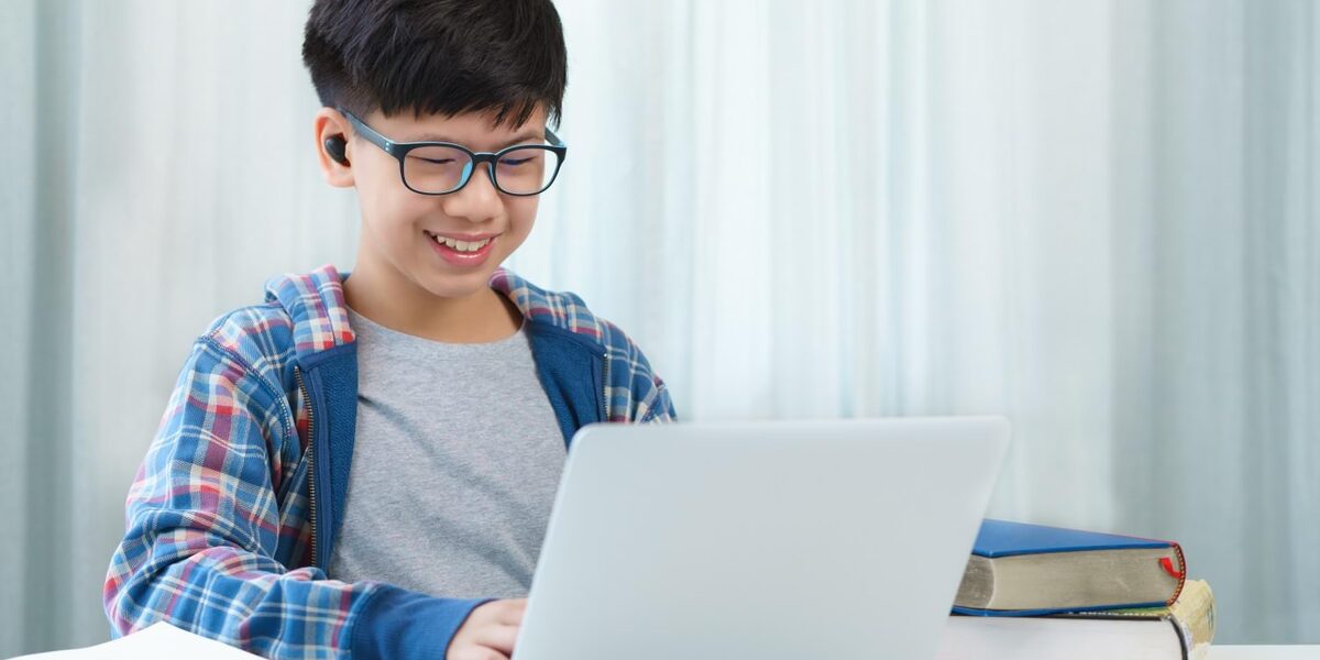 Junge mit DIMS-Brillengläsern vor dem Computer.