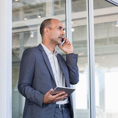 Gschäftsmann mittleren Alters mit iPad telefoniert.