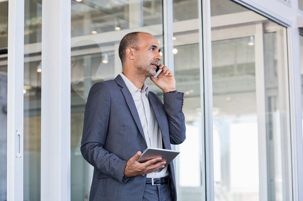 Gschäftsmann mittleren Alters mit iPad telefoniert.