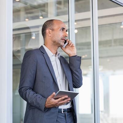 Gschäftsmann mittleren Alters mit iPad telefoniert.