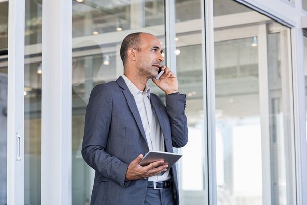 Gschäftsmann mittleren Alters mit iPad telefoniert.
