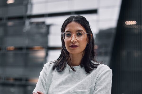 Junge Frau mit Brille blickt in die Kamera.