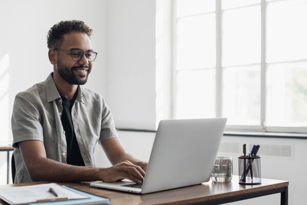 Kurzsichtiger junger Mann arbeitet am Computer