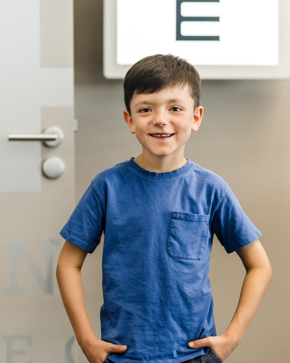 Portrait eines Schuljungen vor einer Sehtafel.
